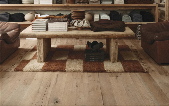 reclaimed wood flooring in cozy living area with books and towels on a wood table and shelves in background