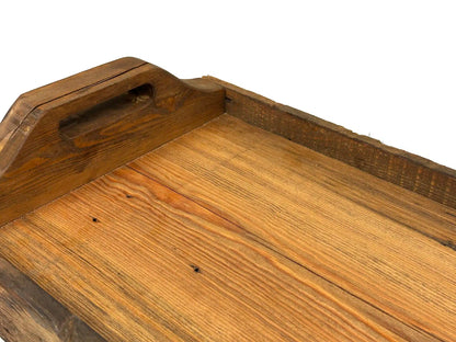 close up of wood characteristics displayed in the reclaimed wood used to create the serving tray. Shows the woods grain and a characteristic called checking which looks like slight cracks. There is a smooth surface of tray itself and rounded handles.