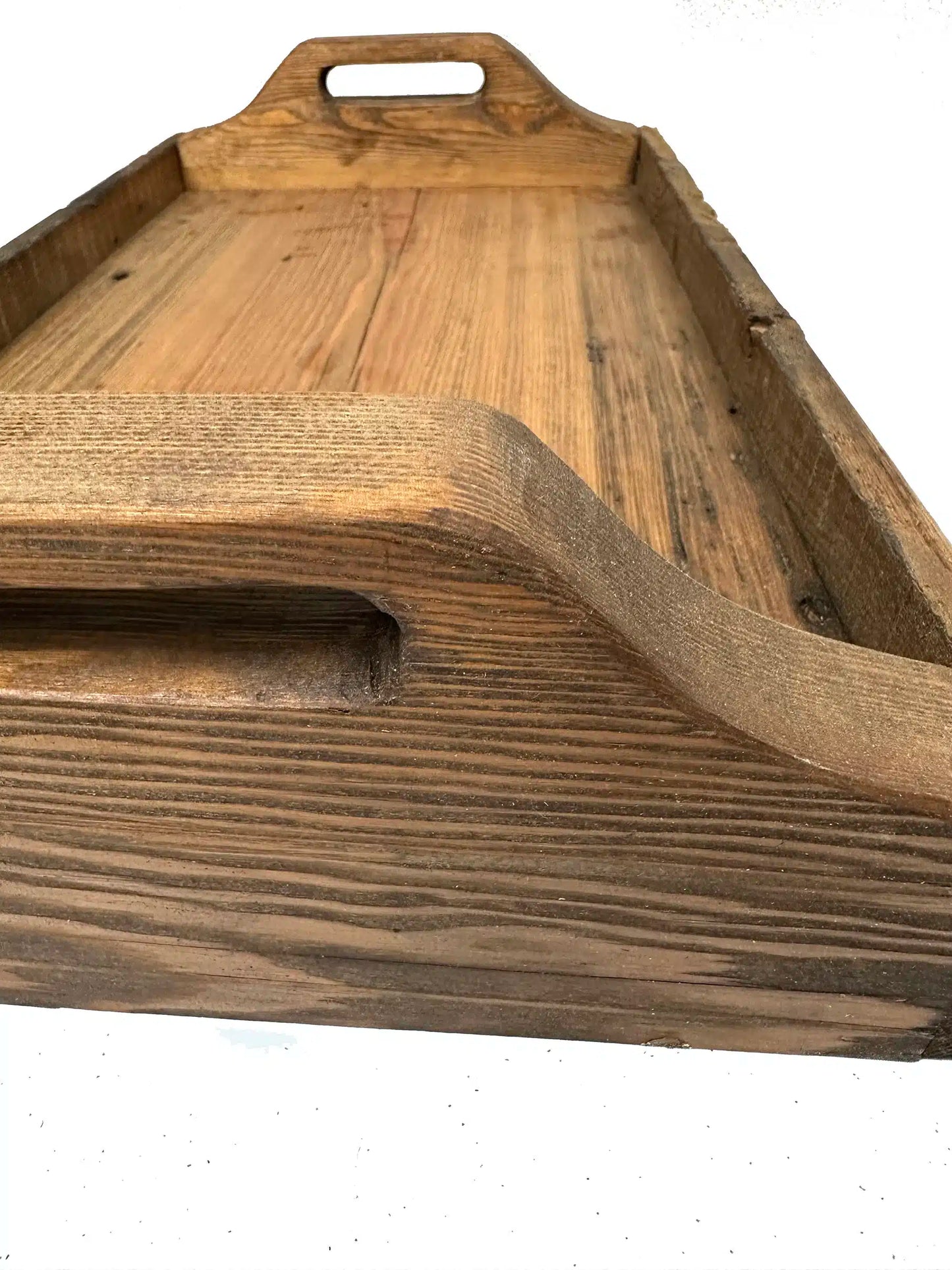 wood serving tray shown from one end. In view is a close up of the handle and grain patterns displayed in the wood.