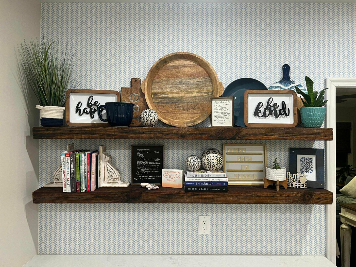 two reclaimed barnwood floating shelves in an oil finish. Shown full of decor, the oil finish highlights signs of past use, grain patterns, and knots in the wood.