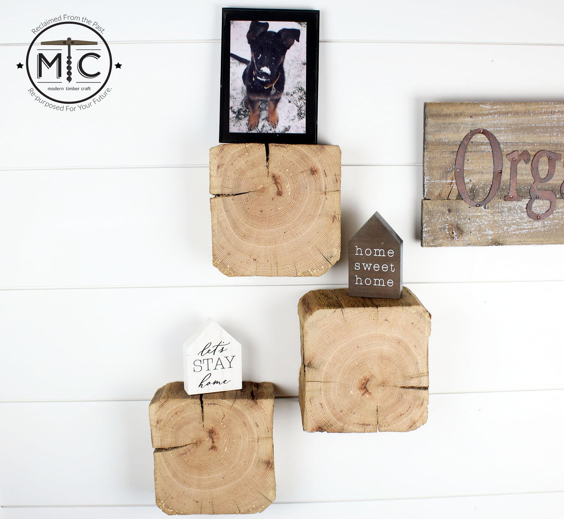 a set of three reclaimed wood wall blocks. The front facing sides are a fresh cut end displaying the growth rings and checking in the wood. The three blocks are staggered on the wall with minimal decor.