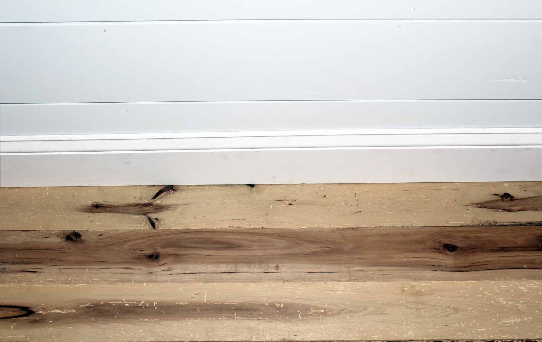 reclaimed hickory flooring installed with baseboard molding. Wood has variations in color and show knots and characteristics from previous bug activity.