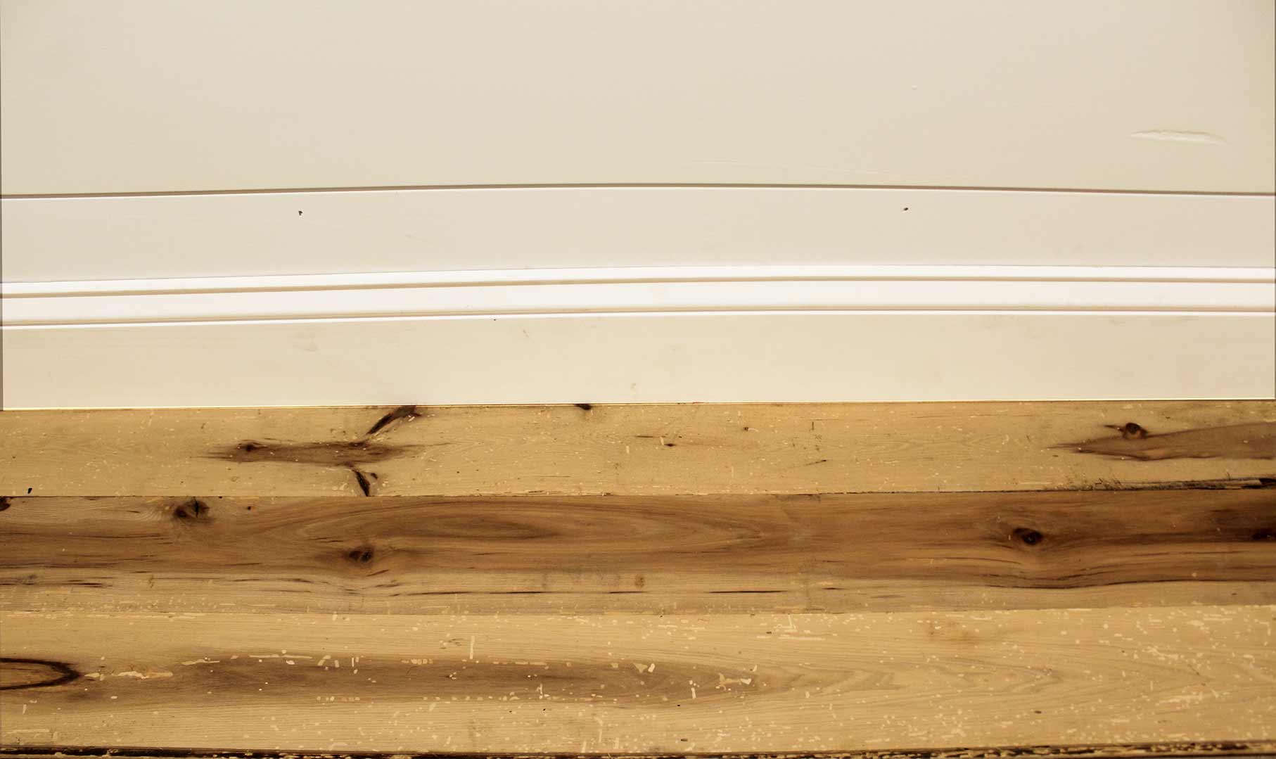 reclaimed hickory flooring installed with baseboard molding. Wood has variations in color and show knots and characteristics from previous bug activity.