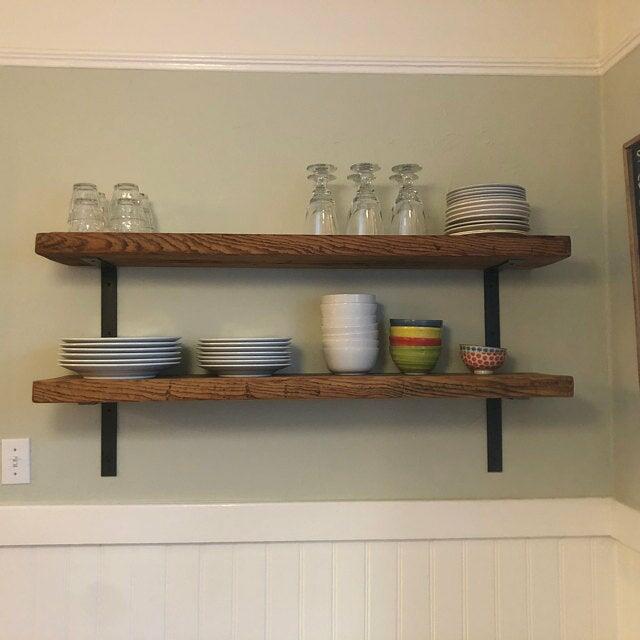 two reclaimed barnwood wall shelves in the natural option. Wood pattern is prominent on the face of the shelves. Shelves are holding plates, bowls, and glassware for a kitchen or dining area.