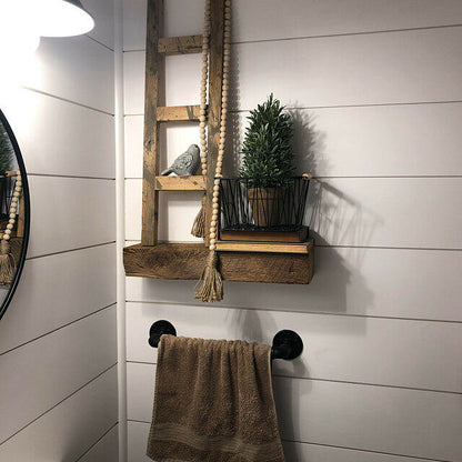 a small reclaimed barnwood floating shelf on a shiplap wall. Shelf is holding a rustic ladder and decor.