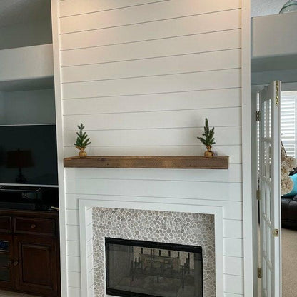 a reclaimed wood floating fireplace mantel in the natural option. Mantel is mounted on a shiplap fireplace with minimal decor.