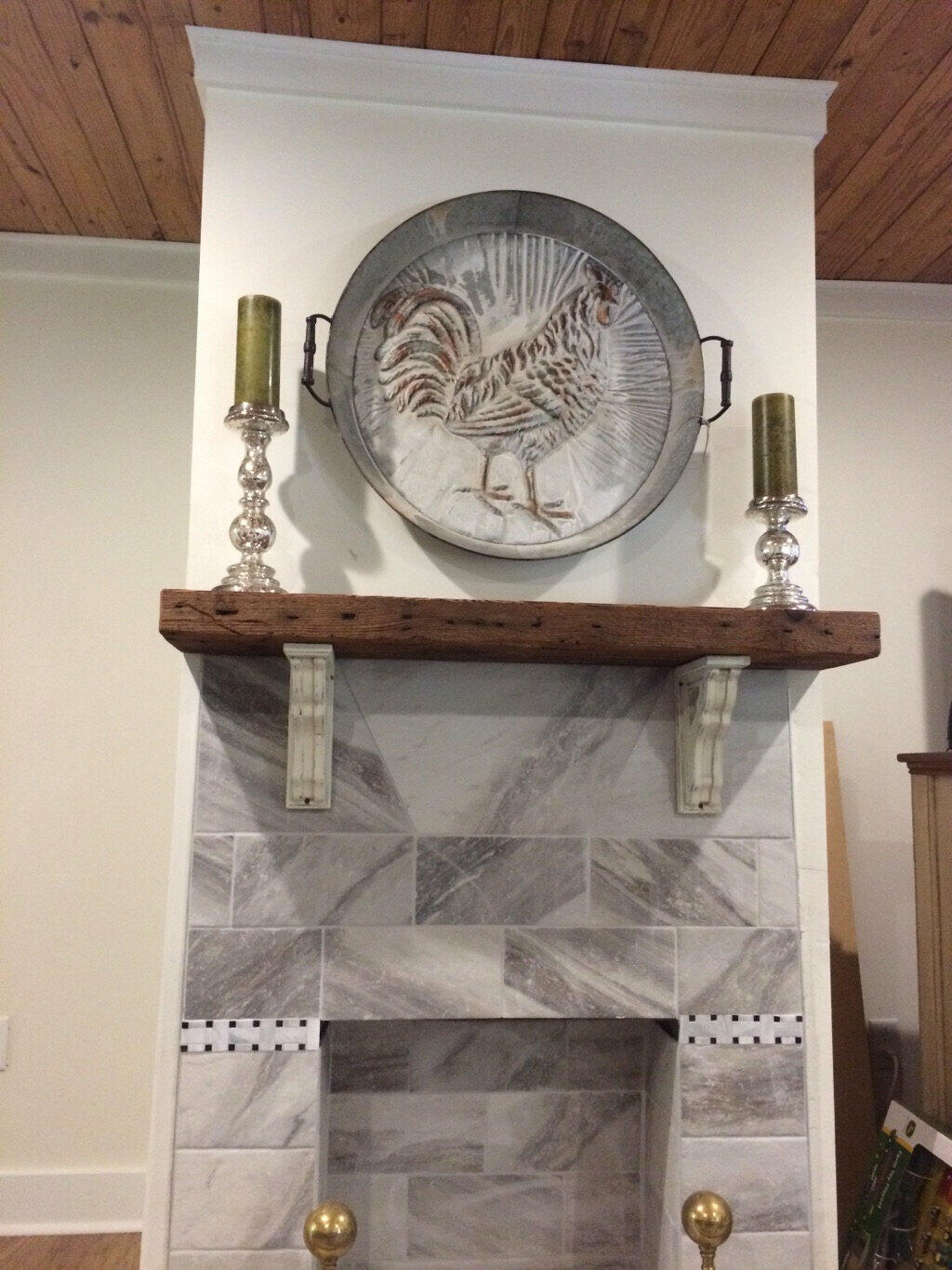 reclaimed barnwood fireplace mantel prominently displayed on a marble fireplace and corbels. Mantel has nail holes displayed proudly across the front.