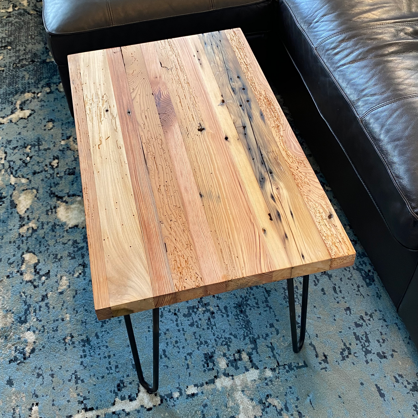 A reclaimed wood coffee table with hair pin legs. The top down view shows variations in the wood and rustic characteristics. The lacquer finish shown adds a slight shine.