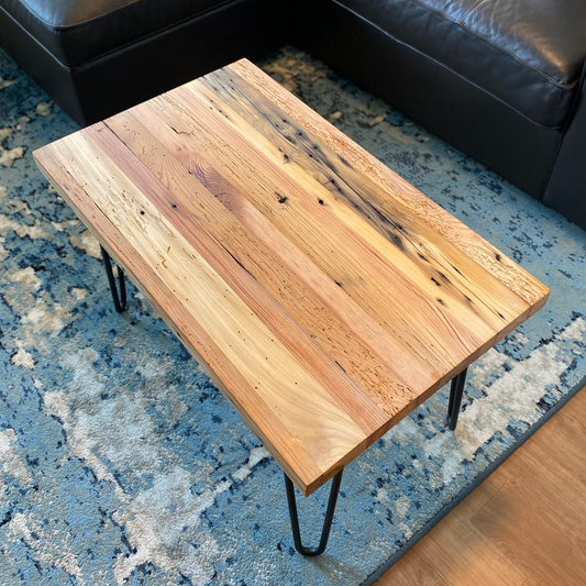 A reclaimed wood coffee table with hair pin legs. The top down view shows variations in the wood and rustic characteristics. The lacquer finish shown adds a slight shine.