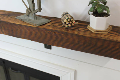a close up of the top side of a skip-planed reclaimed barnwood fireplace mantel in the oil finish. Close up images shows grain pattern and other variations in the wood.