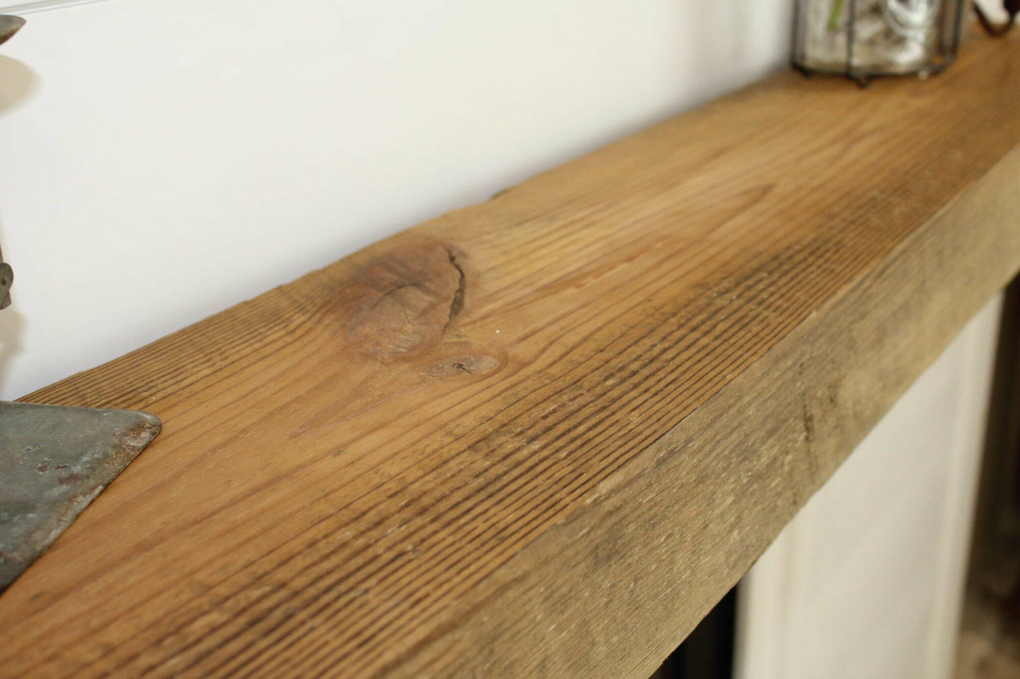 a close up of the top side of a skip-planed reclaimed barnwood fireplace mantel in the natural finish. Close up images shows grain pattern.