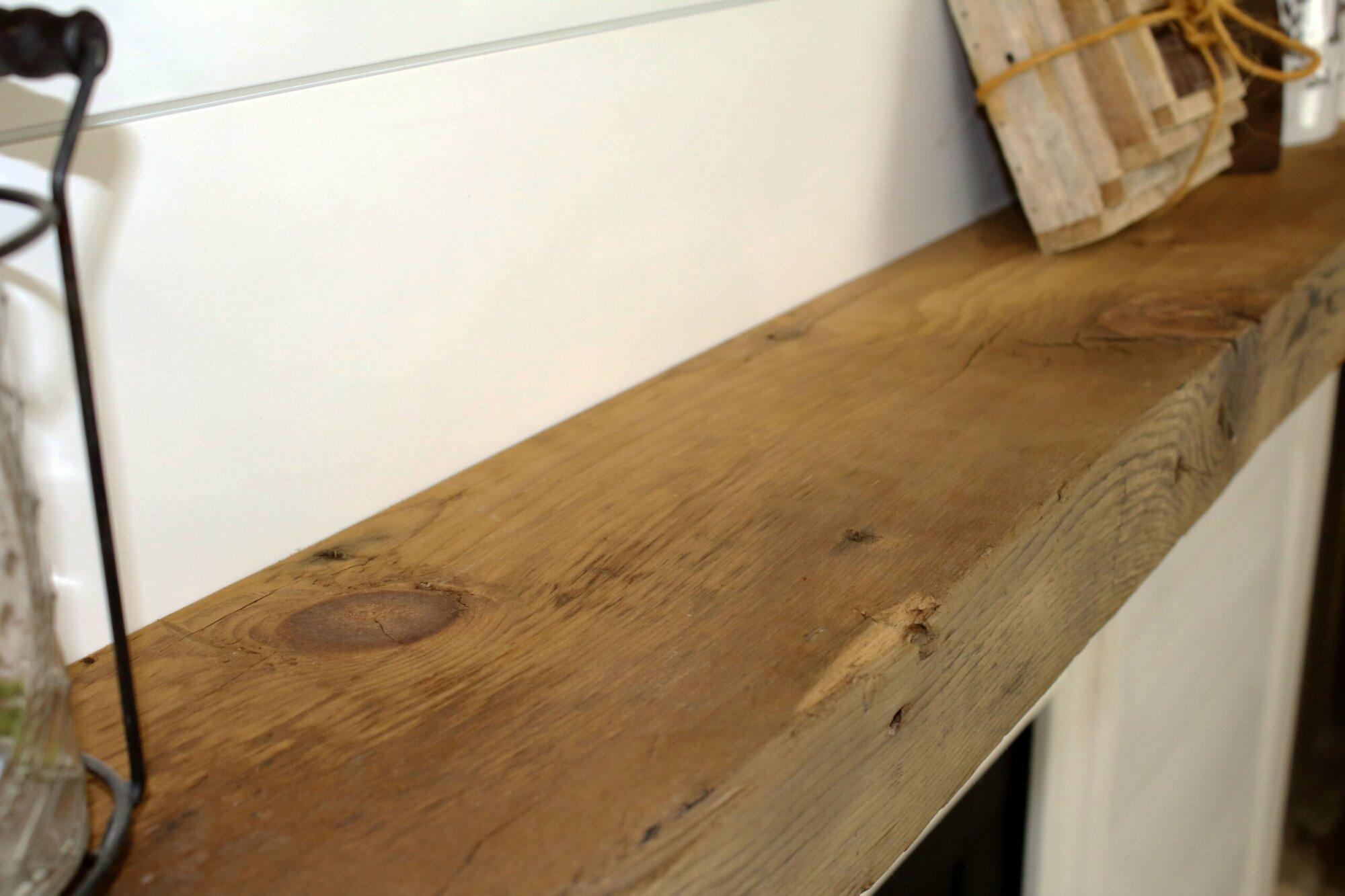 a close up of the top side of a skip-planed reclaimed barnwood fireplace mantel in the natural finish. Close up images shows grain pattern.