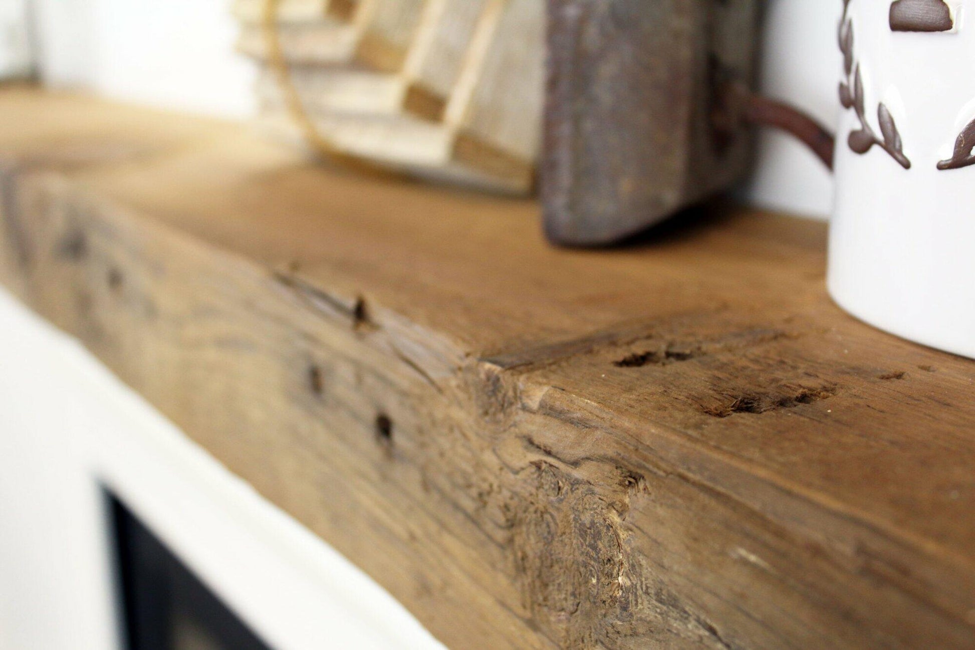 a close up of the top side of a skip-planed reclaimed barnwood fireplace mantel in the natural option. Close up images shows grain pattern, wood texture, knots, nail holes, and other variations in the wood.
