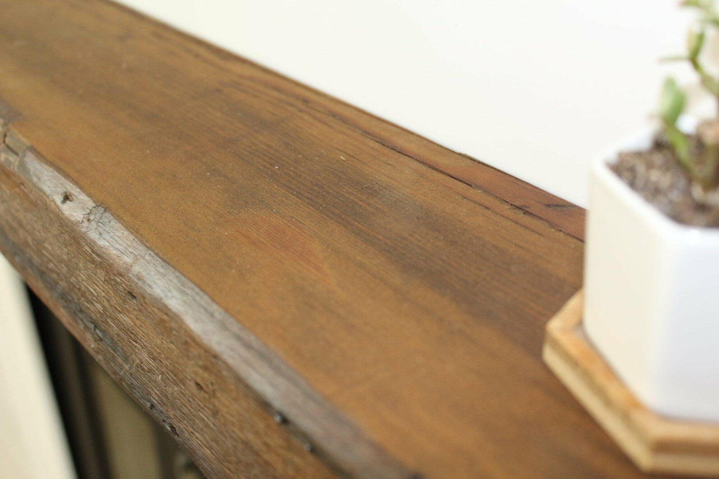 a close up of the top side of a skip-planed reclaimed barnwood fireplace mantel. Close up images shows grain pattern and other variations in the wood.