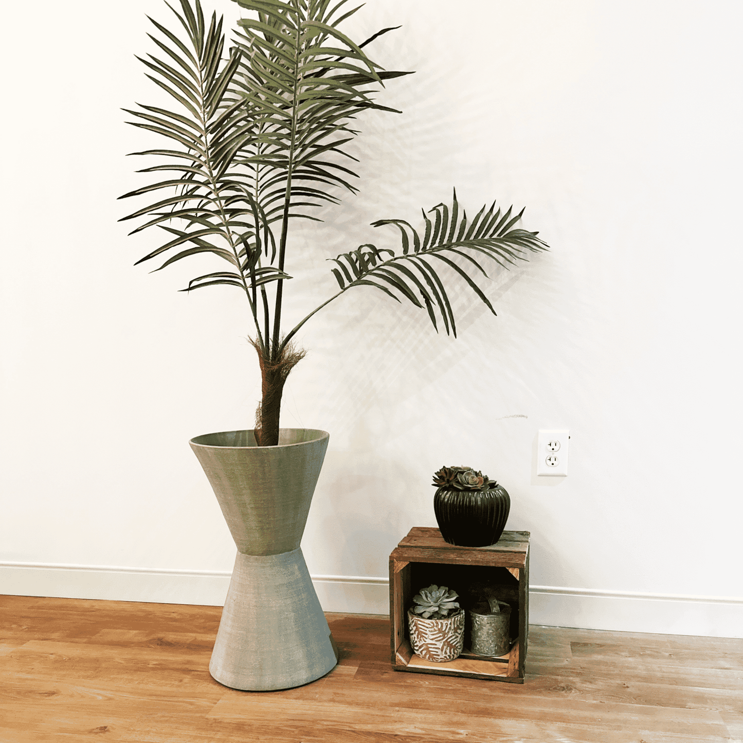 small wooden crate made from reclaimed wood displayed next to a large plant. There is a small plant on top and two inside to show the size of the crate and natural decor.