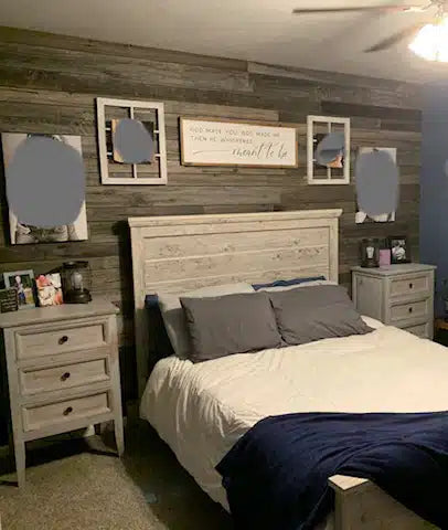 weathered grey barnwood paneling installed on the wall of a bedroom. Variations of color, texture, and characteristics displayed throughout.