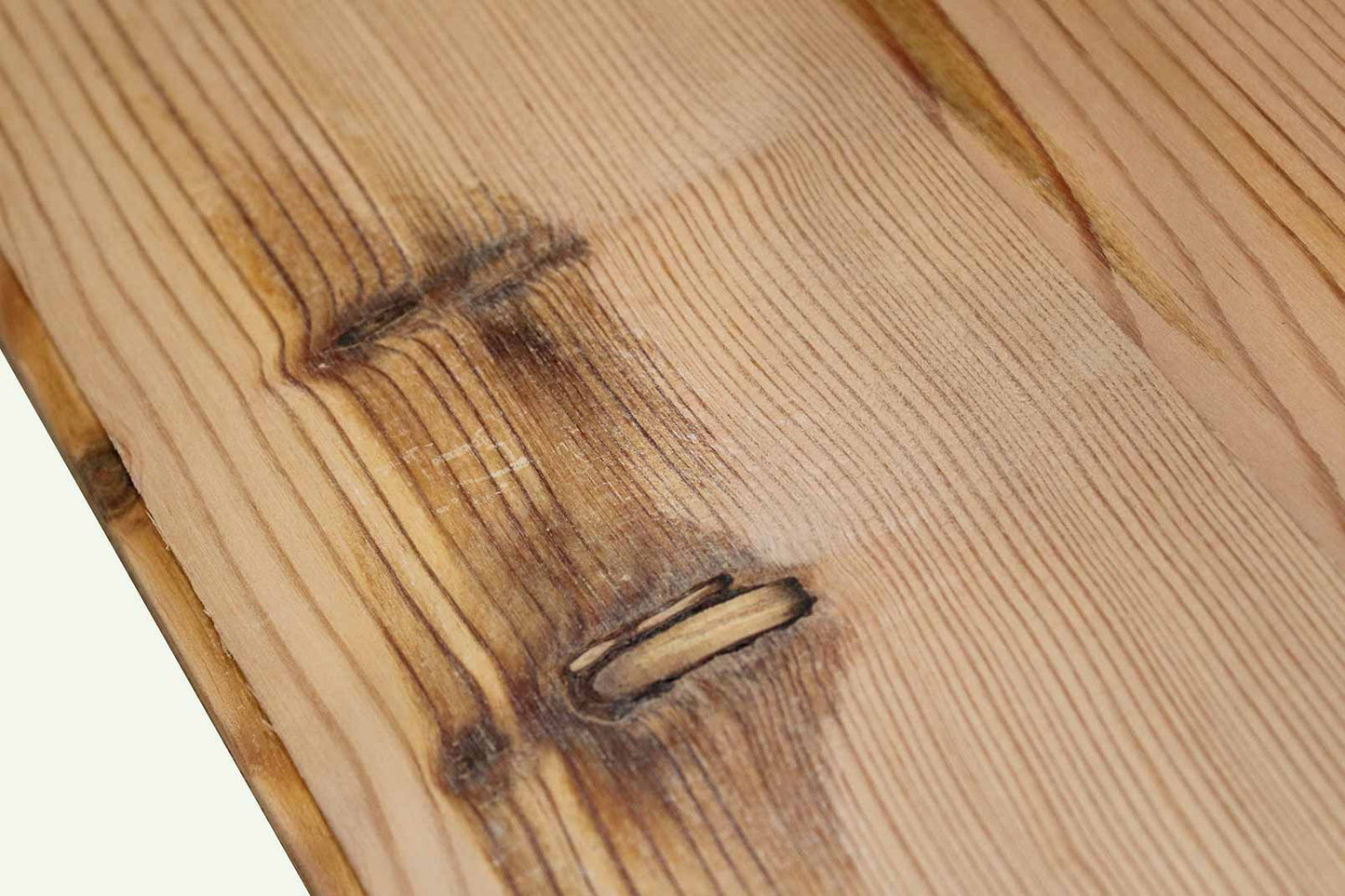 close up of yellow pine reclaimed flooring. Knots shown throughout and grain patterns in the wood are prominent.