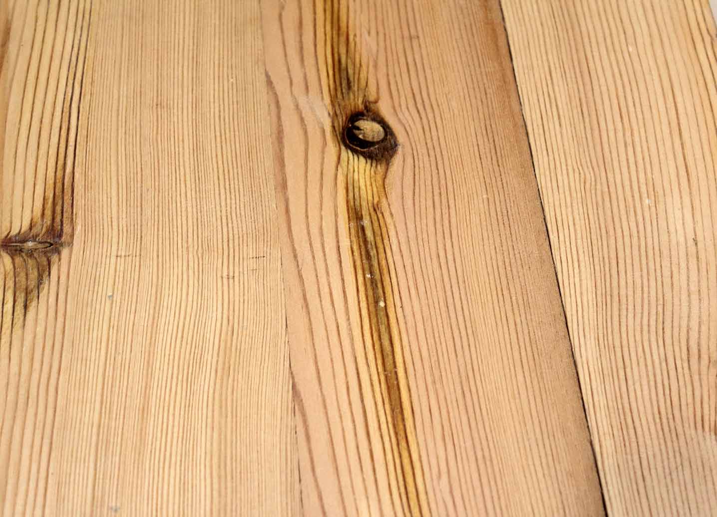 close up of yellow pine reclaimed flooring. Knots shown throughout and grain patterns in the wood are prominent.